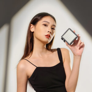 Woman holding Ulanzi LE20 pocket video light next to her face, demonstrating compact handheld size for portrait lighting and content creation